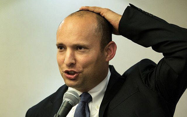 Naftali Bennett, in 2014, gives a speech holding his kippa to his head. (Menahem Kahana/AFP)