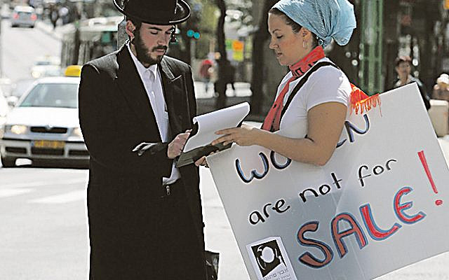 An ultra orthodox man signs a petition at a demonstration for women's rights held outside the Rabbinical court for divorces in Jerusalem on March 19, 2008. Photo by Miriam Alster/Flash90. Via Jewish News