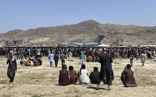 Hundreds of people gather near a US Air Force C-17 transport plane at a perimeter at the international airport in Kabul, Afghanistan, August 16, 2021. Thousands of Afghans trapped by the sudden Taliban takeover rushed the tarmac and clung to US military planes deployed to fly out staffers of the US embassy, which had shut down. (AP Photo/ Shekib Rahmani)