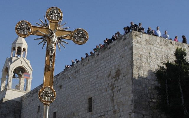 A man carries a cross in front of the Church of the Nativity, believed by Christians to be the birthplace of Jesus, in the West Bank town of Bethlehem during a parade Dec. 24, 2010. (AP Photo/Nasser Shiyoukhi, File)