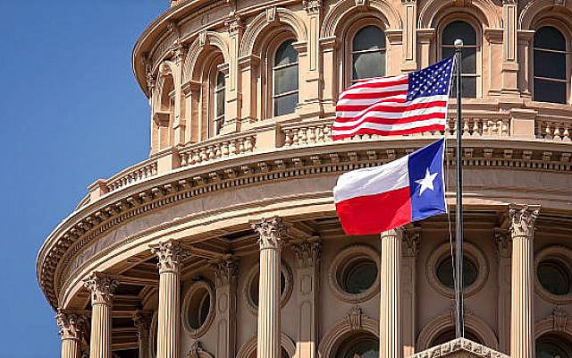 American and Texas state flags flying on the dome of the Texas State Capitol building in Austin
