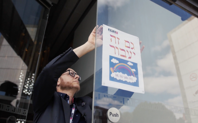 Raymond Simonson putting up a welcoming sign onto the door of JW3 (Credit: Blake Ezra)