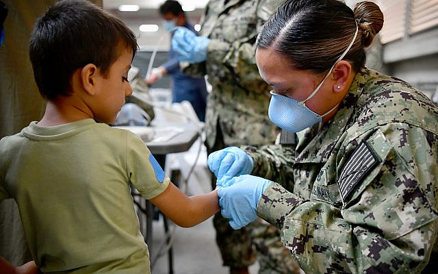 NAVAL AIR STATION SIGONELLA, Italy (Aug. 22, 2021) A U.S. Navy Sailor assists an Afghan evacuee at Naval Air Station (NAS) Sigonella, Aug. 22, 2021.  (U.S. Navy photo by Mass Communication Specialist 1st Class Daniel M. Young: https://www.flickr.com/photos/usnavy/51397690113)