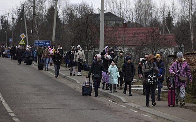 Groups of Ukrainian refugees walk along the road between Lviv and Shehyni, in Volytsya, Ukraine, Saturday March 5, 2022. The number of Ukrainians forced from their country since the Russian invasion has been increasing on a daily basis. (AP Photo/Marc Sanye)