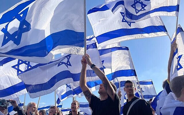 Illustrative: Israelis wave flags outside Jerusalem's Old City on April 20, 2022. (Carrie Keller-Lynn/Times of Israel) Illustrative: Israelis wave flags outside Jerusalem's Old City on April 20, 2022. (Carrie Keller-Lynn/Times of Israel)