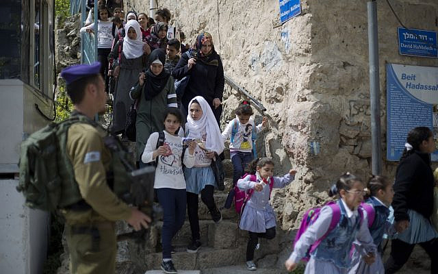 In this March 21, 2019 photo, an Israeli soldier stands guard as Palestinian school children cross back from school in the Israeli controlled part of the West Bank city of Hebron. (AP Photo/Ariel Schalit) In this March 21, 2019 photo, an Israeli soldier stands guard as Palestinian school children cross back from school in the Israeli controlled part of the West Bank city of Hebron. (AP Photo/Ariel Schalit)