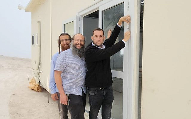 Head of the Samaria Regional Council Yossi Dagan (right) afixes a mezuzah to the new yeshiva in Homesh, May 29, 2023. (Roi Hadi)
