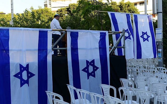 Activists from the Rosh Yehudi organization set up a 'mechitzah' divider made of Israeli flags ahead of a public prayer event in Dizengoff Square, Tel Aviv, on Yom Kippur eve. September 24, 2023. (Tomer Neuberg/Flash 90)