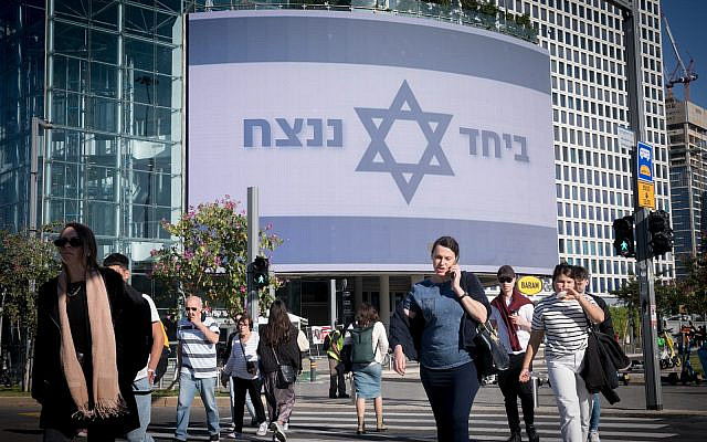 People walk by a large billboard reading "Together we will win" at Azrieli, in Tel Aviv. December 19, 2023. (Miriam Alster/Flash90) People walk by a large billboard reading "Together we will win" at Azrieli, in Tel Aviv. December 19, 2023. (Miriam Alster/Flash90)