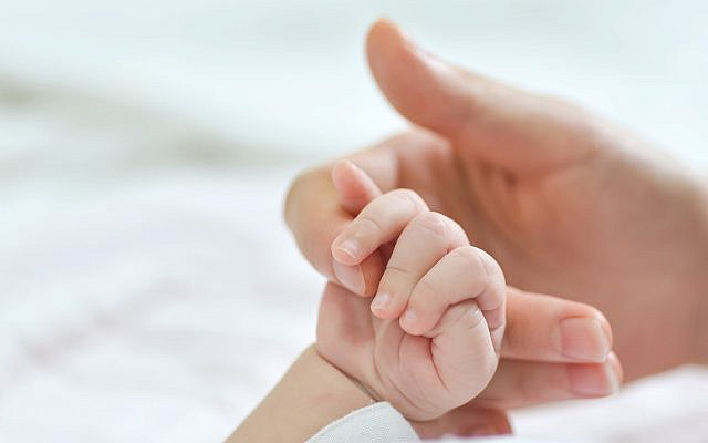 A mother holds the hand of her newborn baby (Freepik)