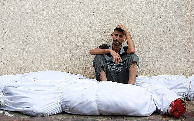 Resigned Palestinian man surrounded by body bags - Wikimedia
