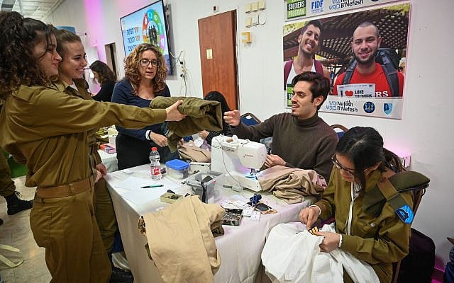 Illustrative. An IDF Lone Soldier hands a tailor a pair of trousers during an annual 'Errands Day' event in Tel Aviv on February 13, 2020. (Shahar Azran/ Nefesh B'Nefesh/ File )