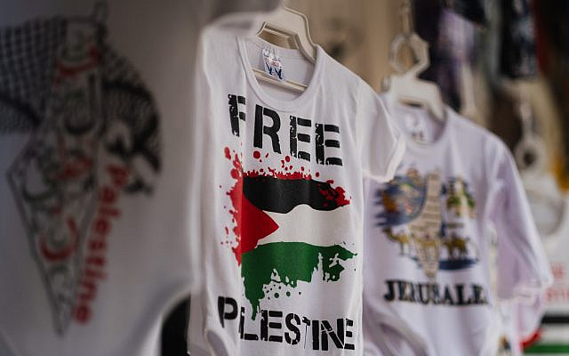 At his shop in Jerusalem, an Arab man sells baby onesies featuring blood gushing from his preferred flag. Photo by the author. At his shop in Jerusalem, an Arab man sells baby onesies featuring blood gushing from his preferred flag. Photo by the author.