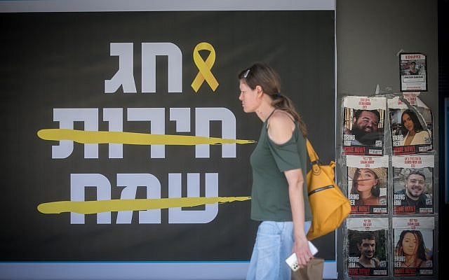 A woman walks by a sign reading 'Happy Freedom Holiday' referring to the holiday of Passover, with the words "Happy" and "Freedom" crossed out, in Tel Aviv. April 16, 2024. (Miriam Alster/Flash90) A woman walks by a sign reading 'Happy Freedom Holiday' referring to the holiday of Passover, with the words "Happy" and "Freedom" crossed out, in Tel Aviv. April 16, 2024. (Miriam Alster/Flash90)