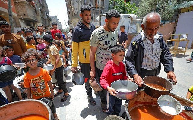 Palestinians receive meals from volunteers in Deir al-Balah, in the Gaza Strip, on April 19, 2025. (Ali Hassan/Flash90)