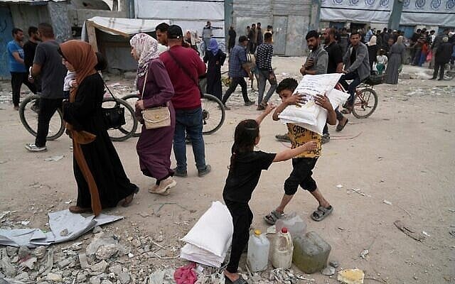 Palestinians receive bags of flour and other humanitarian aid distributed by UNRWA, the UN agency for Palestinian refugees, in Jabalia, Gaza Strip, April 1, 2025. (AP/Jehad Alshrafi) (The Times of Israel)