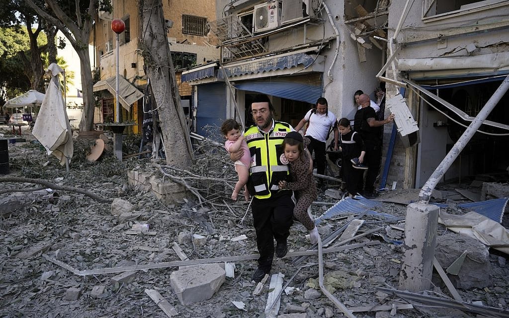 A rescue worker carries two children as residents evacuate from the site where a missile launched from Iran struck Haifa, Sunday, June 22, 2025. (AP Photo/Baz Ratner)