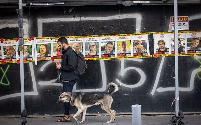 A man walks his dog past posters of Israelis held hostage in Gaza, in Tel Aviv. January 28, 2025. (Miriam Alster/FLASH90) A man walks his dog past posters of Israelis held hostage in Gaza, in Tel Aviv. January 28, 2025. (Miriam Alster/FLASH90)