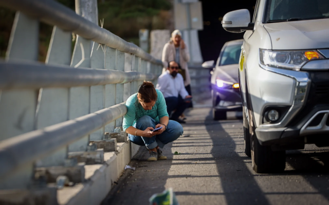 People take cover at the side of the road as a siren warns of incoming missile fired from Yemen, on Route 16, outside Jerusalem, May 14, 2025 (Yossi Zamir/Flash90)