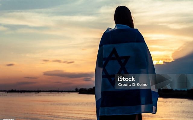 Woman with Israel flag against sunset sky