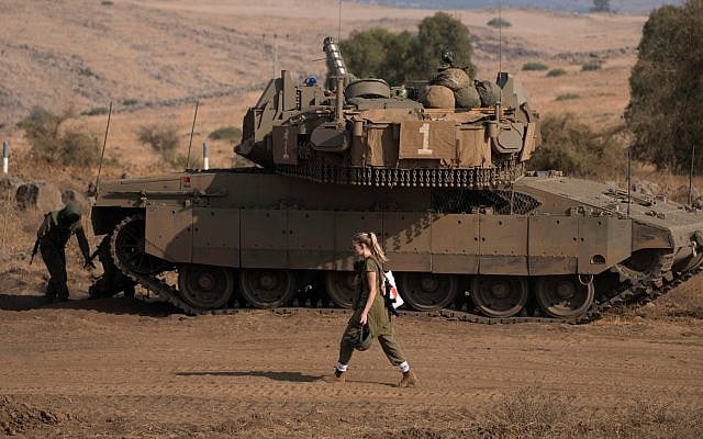A Israeli soldier walks in front of a tank near the border with Lebanon, Saturday, October 14, 2023. (AP Photo/Petros Giannakouris)
