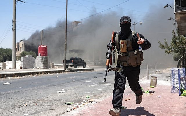 Heavy smoke rises as a member of Bedouin and tribal forces runs during clashes with Druze fighters in Syria's southern city of Sweida on July 19, 2025. (OMAR HAJ KADOUR / AFP)