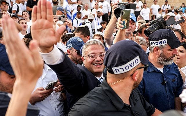 National Security Minister Itamar Ben-Gvir, surrounded by Israeli policemen, waves to other right-wing activists gathering outside the Damascus Gate of the walled Old City of Jerusalem on May 26, 2025, during a flag march for Jerusalem Day, commemorating the Israeli army's 1967 capture of the city's eastern sector. (AHMAD GHARABLI / AFP)