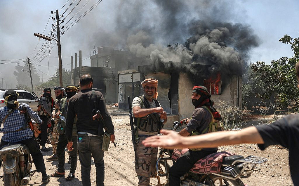 Bedouin fighters gather in front a burning shop at Mazraa village on the outskirts of Sweida, Syria, on July 18, 2025. (AP/Ghaith Alsayed)