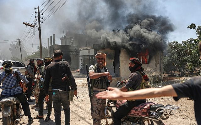 Bedouin fighters gather in front a burning shop at Mazraa village on the outskirts of Sweida, Syria, on July 18, 2025. (AP/Ghaith Alsayed)