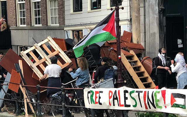 Protesters reinforce a barricade at the Oudemanhuispoort encampment on May 7, 2024, blocking Oudezijds Achterburgwal as banners hang along the fences. Photo: Umbrellafighter, CC BY-SA 4.0, via Wikimedia Commons. Protesters reinforce a barricade at the Oudemanhuispoort encampment on May 7, 2024, blocking Oudezijds Achterburgwal as banners hang along the fences. Photo: Umbrellafighter, CC BY-SA 4.0, via Wikimedia Commons.