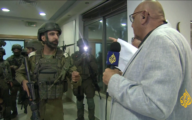 IDF soldiers hand an Al Jazeera reporter a military order directing the closure of his Ramallah office during a raid of the bureau on September 22, 2024. (Screen capture)