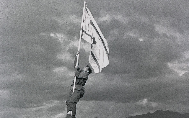 The Ink Flag was a handmade Israeli flag raised in March 1949 at Umm Rashrash (now Eilat), marking Israel’s capture of the area, the end of the 1948 Arab–Israeli War, and the birth of Israel. A photograph by Micha Perry. The Ink Flag was a handmade Israeli flag raised in March 1949 at Umm Rashrash (now Eilat), marking Israel’s capture of the area, the end of the 1948 Arab–Israeli War, and the birth of Israel. A photograph by Micha Perry.