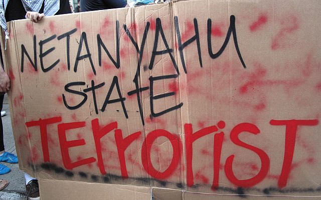 Protesters brandish a cardboard sign denouncing Netanyahu as a “state terrorist” during a street demonstration. (Rebecca W/Flickr)
