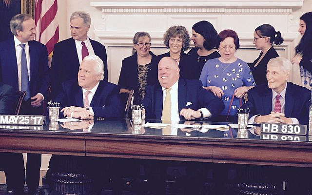 Ruth Berlin, founder of the Maryland Pesticide Education Network (MPEN), stands behind then Maryland Governor Larry Hogan as he signs progress on pollinators. Photo courtesy of MPEN.