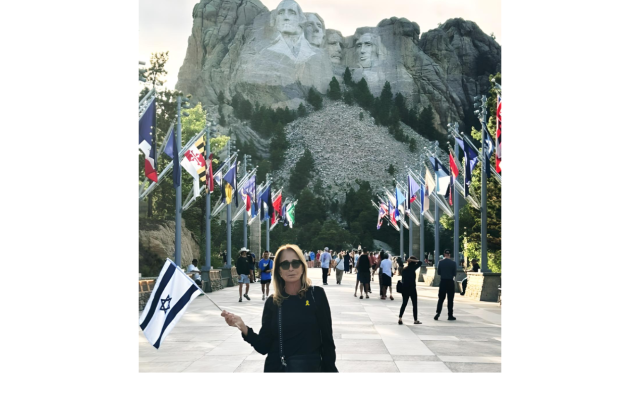 The author at Mount Rushmore, holding the Israeli flag — a call for peace, unity, and justice.