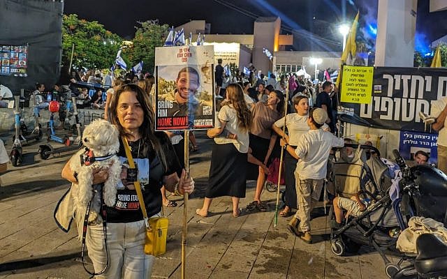 Hagit Chen, the mother of fallen hostage Itay Chen, poses with Itay's dog, in Hostages Square after Simhat Torah in Tel Aviv, October 14, 2025. (Deborah Danan/ JTA, via The Times of Israel)