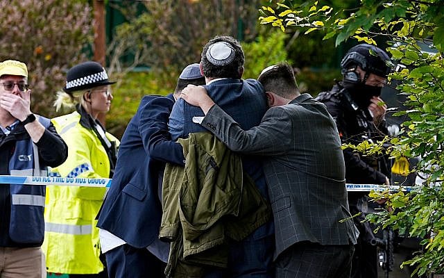 Members of the Jewish community comfort each other near the Heaton Park Hebrew Congregation synagogue, in Crumpsall, Manchester, England, October 2, 2025. (Peter Byrne/ PA via AP)