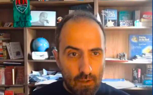 Author and Podcaster Vitor Vicente in front of bookshelf with Jewish and cultural objects.