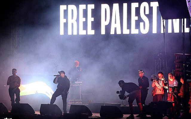 Illustrative. Liam O'Hanna (2L) from Northern Irish Hip Hop trio Kneecap performs with bandmates Naoise O Caireallain (L) and JJ O'Dochartaigh, beneath a 'Free Palestine' sign onstage during Wide Awake Festival at Brockwell Park in south London, on May 23, 2025. (HENRY NICHOLLS / AFP)