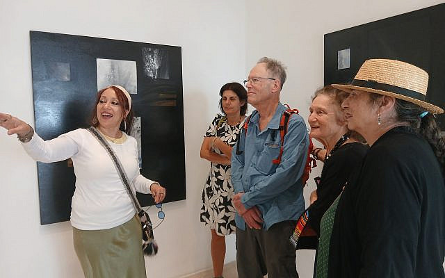 Raquel Sanchez introducing her works to visitors—pieces where words and pale lines emerge from darkness like whispered prayers. (Photo: Bonnie K. Goodman)