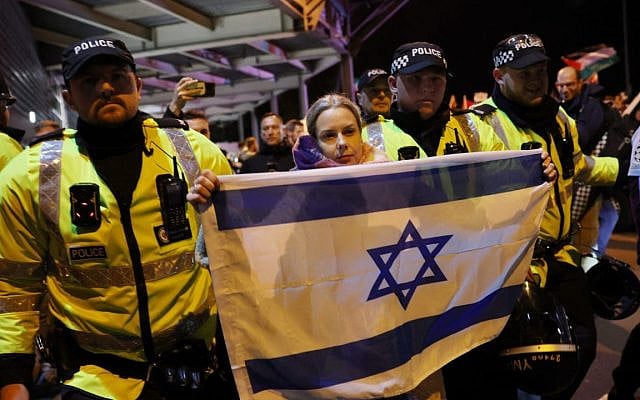 Police officers escort a woman with an Israeli flag away from pro-Palestinian protesters outside Villa Park. (AFP)