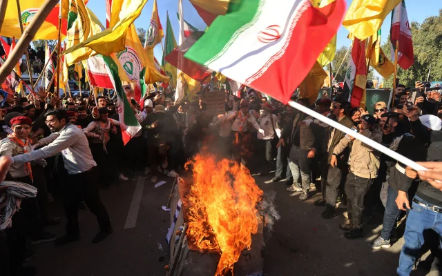 Supporters of Iraqi armed factions loyal to Iran, along with other protesters, burn US and Israeli flags during a demonstration near the Iranian embassy in Baghdad on January 16, 2026. (Photo by AHMAD AL-RUBAYE / AFP)