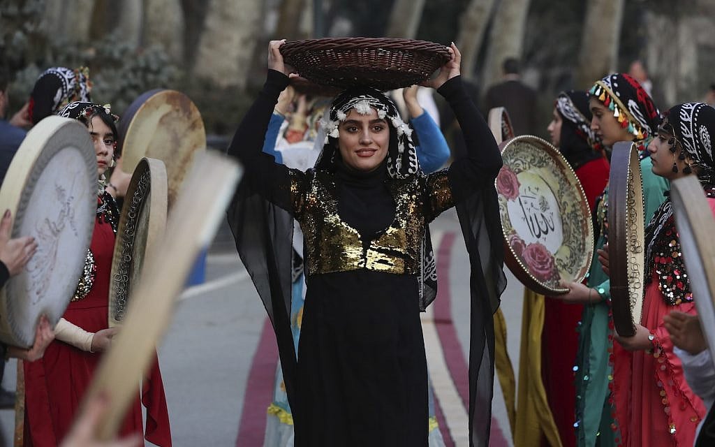 A woman carries a basket of pomegranates above her head as musicians from the Kurdish western region of Iran play Daf, a hand-held Persian drum, in a public celebration of the ancient feast of Yalda, at the Saadabad Palace in northern Tehran, Iran, Saturday, Dec. 21, 2019. (AP Photo/Vahid Salemi)