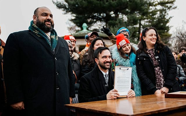 New York City Mayor Zohran Mamdani, center, joined by Ali Najmi, left, chair of the Mayor's Advisory Committee on the Judiciary, and Tascha Van Auken, right, commissioner of the Mayor's Office of Mass Engagement, holds up a signed executive order during a press conference in New York, Friday, Jan. 2, 2026. (AP Photo/Eduardo Munoz Alvarez)