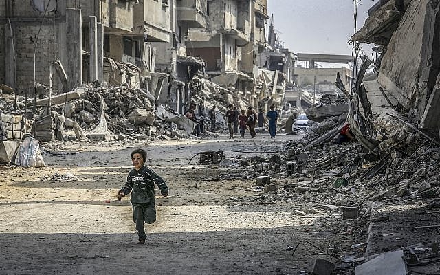 Palestinians walk past buildings destroyed in the recent war, in Khan Yunis, southern Gaza Strip, November 6, 2025. (Abed Rahim Khatib/Flash90)