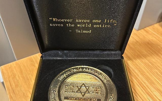 A commemorative coin given to the author by a Jewish doctor from the host community abroad after he helped save a fellow veteran’s life, inscribed with the Talmudic phrase “Whoever saves one life, saves the world entire.” (Photo credit: Eitan Sermoneta)