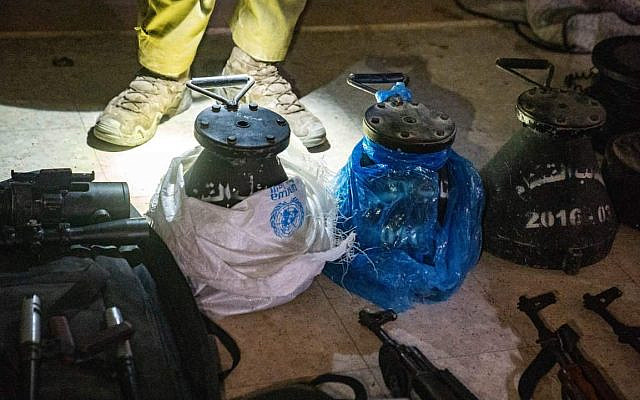 Weapons and munitions shown alongside UNRWA-marked aid bags and blankets, on February 3, 2026. The IDF states that approximately 110 mortar shells and additional weapons were discovered concealed within those items. (Israel Defense Forces)