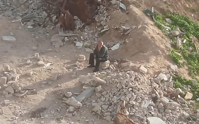 A photo taken in mid-2025 of Khalil El-Halabi sitting on the rubble of his home in northern Gaza. The site is no longer accessible to him because it lies beyond the Israeli yellow line. (Courtesy)