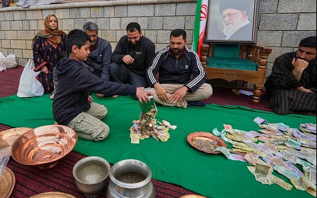 A boy empties his piggy bank to donate his savings during a relief drive for Iran in Budgam, Kashmir, India. Monday, March 23, 2026. (Photo Credit: AP Photo/Mukhtar Khan)
