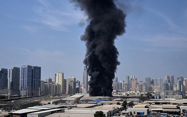 A black plume of smoke rises from a warehouse at the industrial area of Sharjah City in the United Arab Emirates following reports of Iranian strikes in Dubai, United Arab Emirates, Sunday, March 1, 2026. (AP Photo/Altaf Qadri)